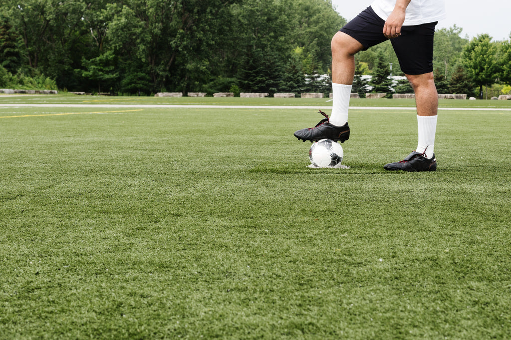 Image of a soccer player cleaning his soccer boots with a brush and a cloth. Our service includes cleaning and maintaining your soccer boots to keep them in top condition.